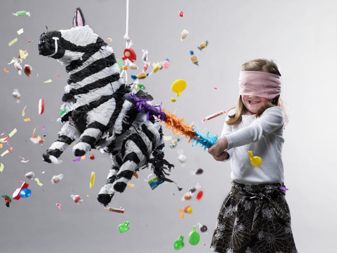 Young girl hitting pinata, candy flying
