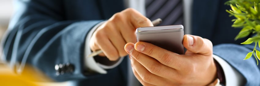 Male arm in suit hold phone and silver pen
