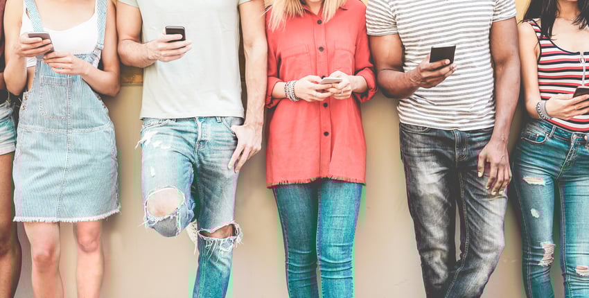Group of millennial friends looking at their smart phones