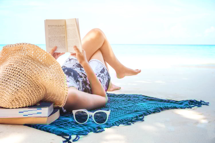 Woman reading a book on the beach in free time summer holiday