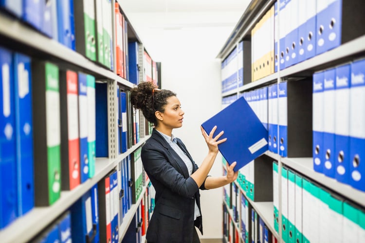 Woman searching for retirement plan files in paper archive