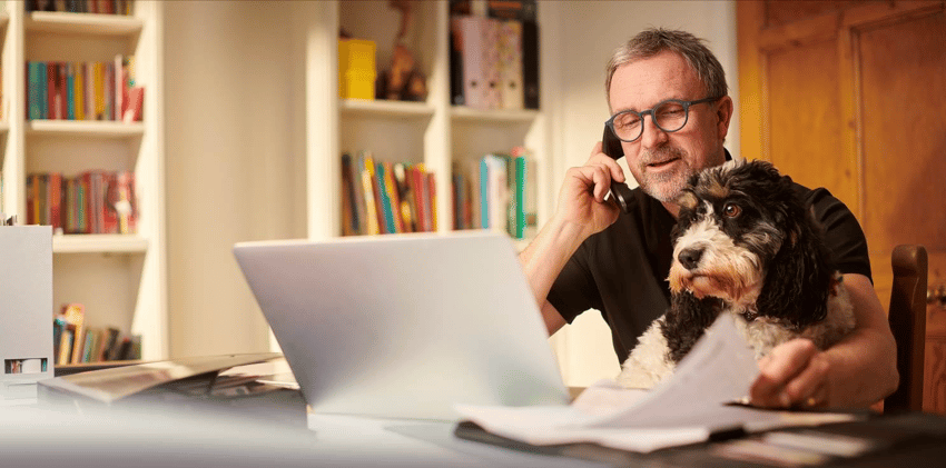 Man on the phone at desk with laptop and dog budgeting for retirement