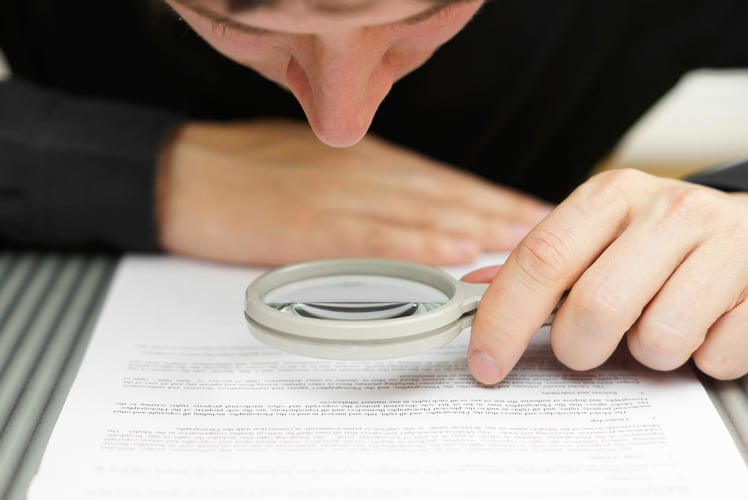 Businessman looking through a magnifying glass to document showing ROI on TDF