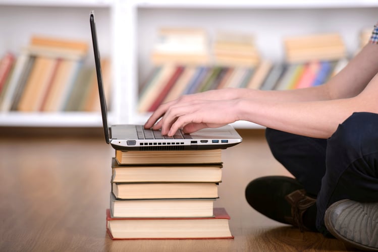 Student researching allowable plan expenses on a laptop in library