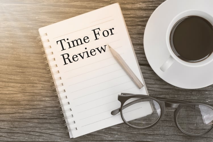 Concept Time For Review message on notebook with glasses, pencil and coffee cup on wooden table.
