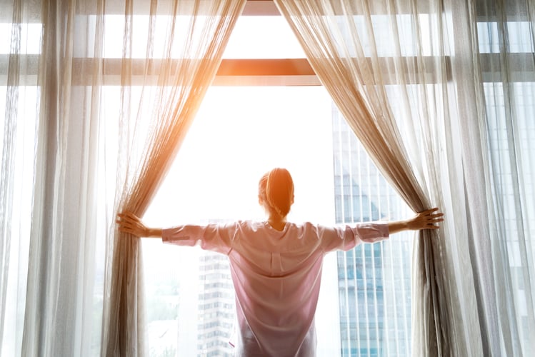 Woman opening curtains and looking out