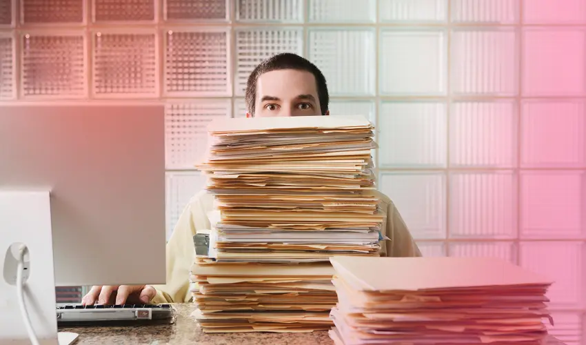 man sitting behind a stack of files