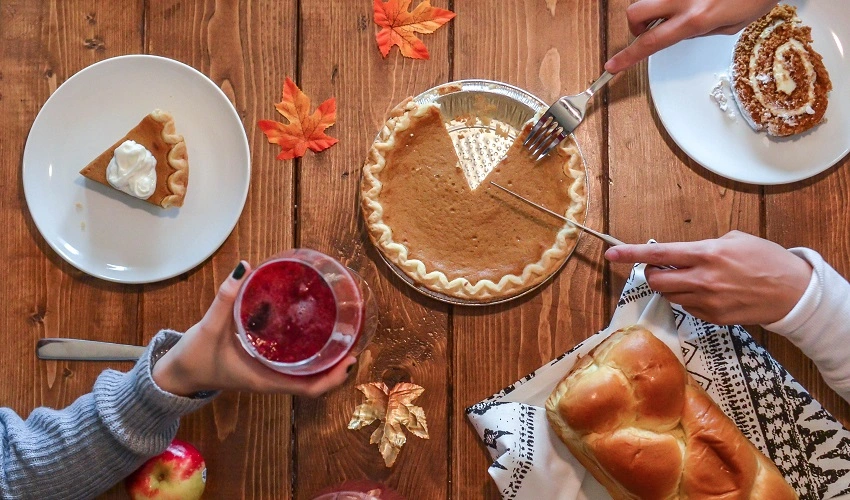 Hands with utensils cutting a piece of pumpkin pie